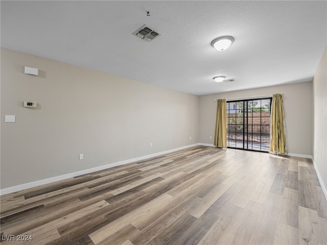 empty room featuring a textured ceiling and hardwood / wood-style flooring