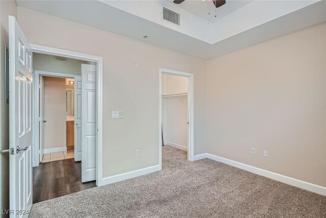 unfurnished bedroom featuring a closet, carpet floors, ceiling fan, and a spacious closet