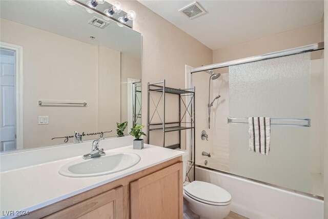 full bathroom with vanity, shower / bath combination with glass door, and toilet