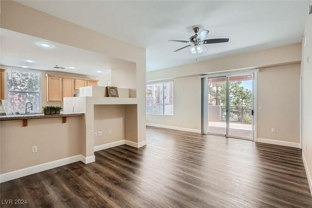 unfurnished living room featuring ceiling fan, sink, and dark hardwood / wood-style flooring