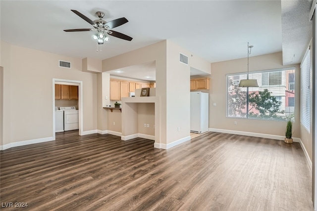 unfurnished living room featuring independent washer and dryer, dark hardwood / wood-style floors, and ceiling fan