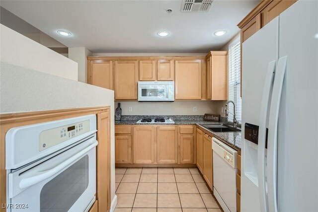 kitchen with sink, light tile patterned floors, light brown cabinetry, and white appliances