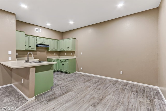 kitchen featuring sink, light hardwood / wood-style flooring, green cabinetry, a kitchen bar, and kitchen peninsula