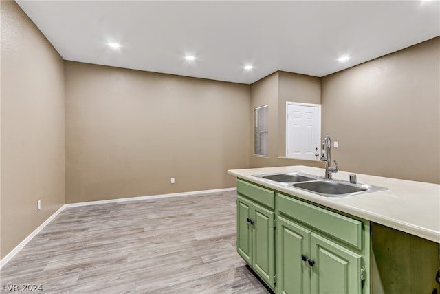 kitchen with green cabinets, sink, and light wood-type flooring