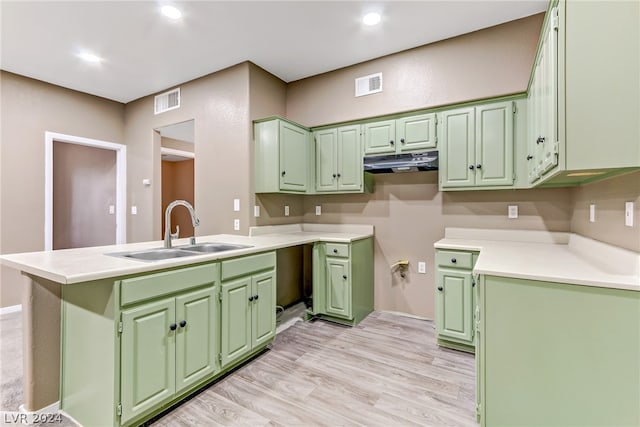 kitchen featuring green cabinetry, a sink, light wood-style flooring, under cabinet range hood, and visible vents