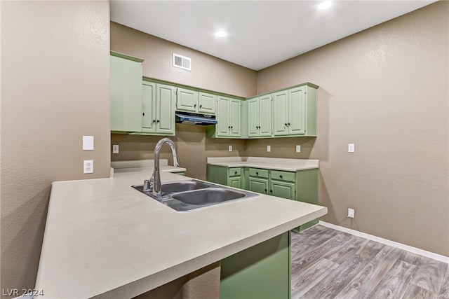 kitchen with sink, kitchen peninsula, green cabinets, and light wood-type flooring