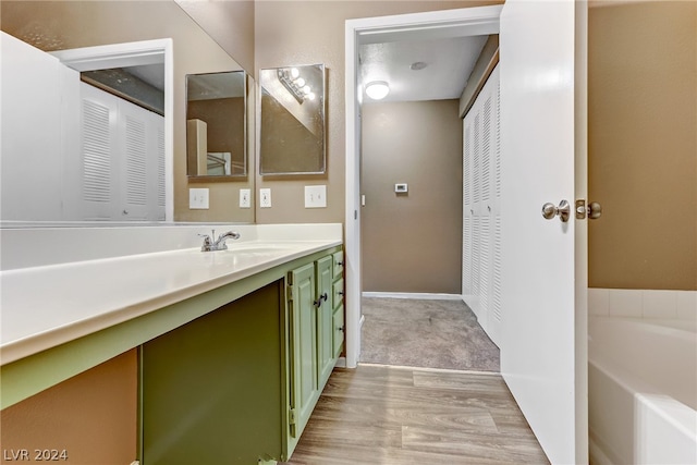 full bathroom featuring a bath, baseboards, wood finished floors, and vanity