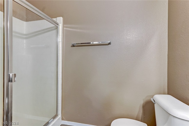 full bath with a stall shower, baseboards, toilet, and a textured wall