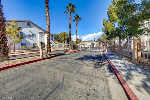 view of road with a gate, curbs, a residential view, sidewalks, and a gated entry