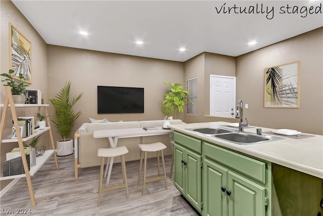 kitchen featuring green cabinetry, light countertops, a sink, open floor plan, and recessed lighting