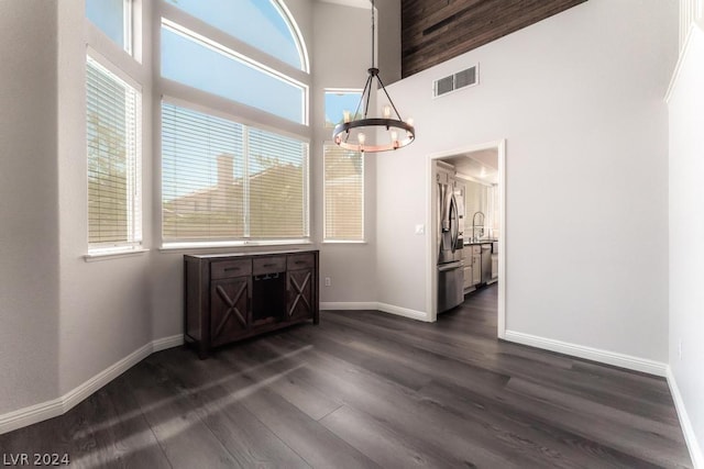 unfurnished dining area with dark wood-type flooring, plenty of natural light, and a towering ceiling