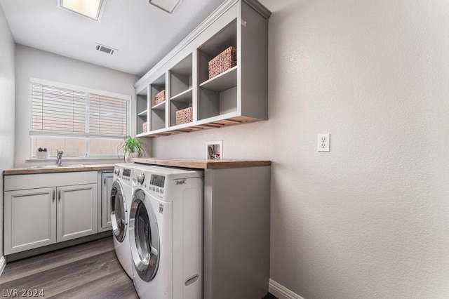 laundry room featuring cabinets, washer and dryer, dark hardwood / wood-style floors, and sink