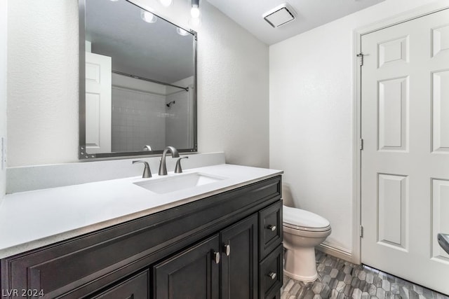 bathroom featuring toilet, vanity, and a tile shower