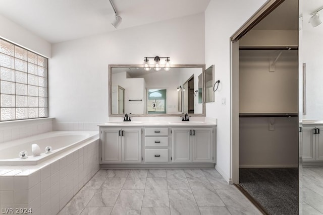 bathroom featuring tiled bath and vanity