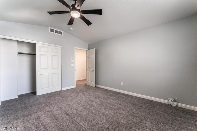 unfurnished bedroom with vaulted ceiling, ceiling fan, a closet, and dark carpet