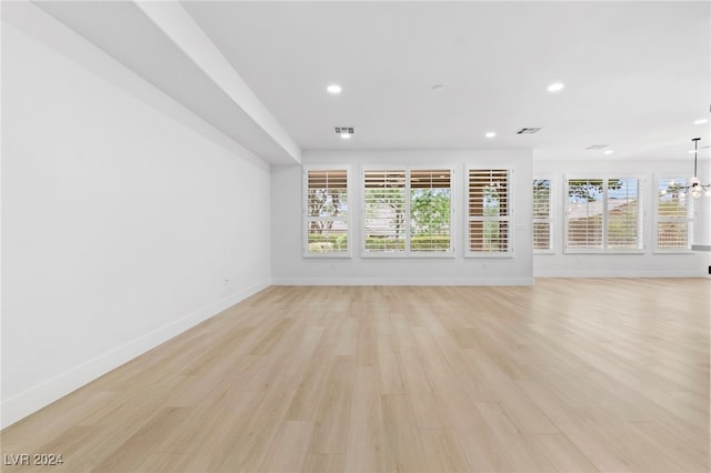 unfurnished living room featuring a chandelier and light wood-type flooring