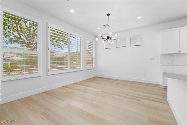 unfurnished dining area with light hardwood / wood-style flooring and a chandelier