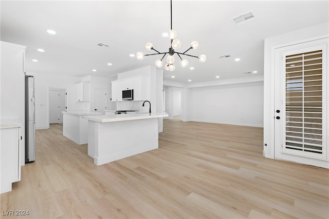 kitchen featuring white cabinets, pendant lighting, light hardwood / wood-style flooring, and a notable chandelier