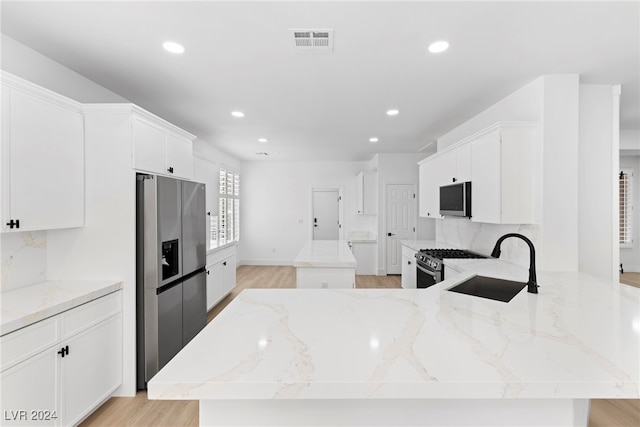 kitchen featuring light stone counters, appliances with stainless steel finishes, and sink