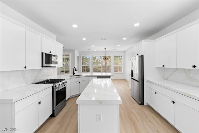 kitchen featuring hanging light fixtures, decorative backsplash, a kitchen island, appliances with stainless steel finishes, and sink