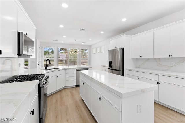 kitchen featuring hanging light fixtures, a kitchen island, light wood-type flooring, backsplash, and appliances with stainless steel finishes