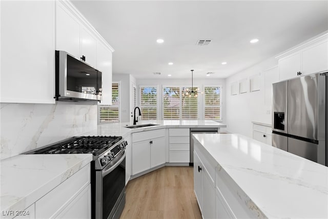 kitchen with sink, decorative light fixtures, white cabinetry, an inviting chandelier, and appliances with stainless steel finishes