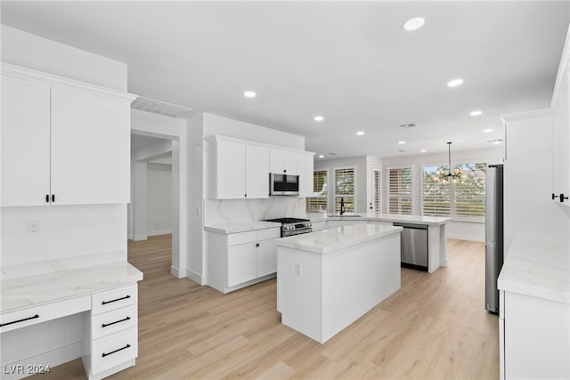 kitchen featuring stainless steel appliances, hanging light fixtures, kitchen peninsula, a kitchen island, and white cabinetry