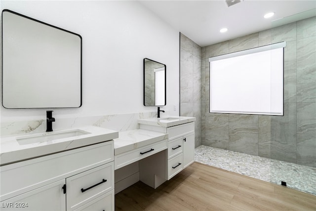 bathroom with hardwood / wood-style flooring, a tile shower, and vanity