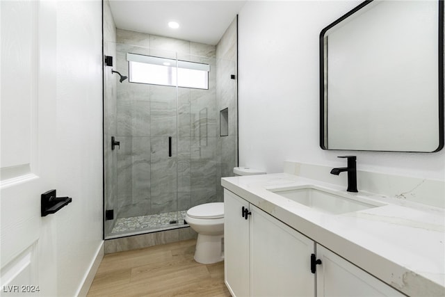 bathroom featuring toilet, vanity, a shower with shower door, and hardwood / wood-style floors