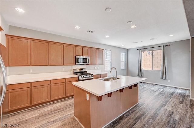 kitchen featuring sink, appliances with stainless steel finishes, a kitchen breakfast bar, an island with sink, and light wood-type flooring