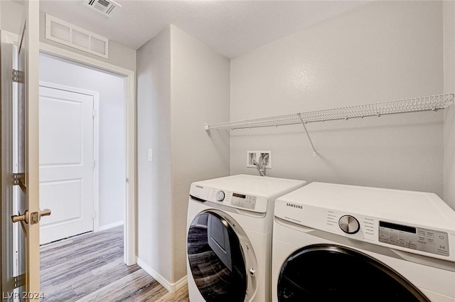 laundry room with washer and clothes dryer and light hardwood / wood-style flooring