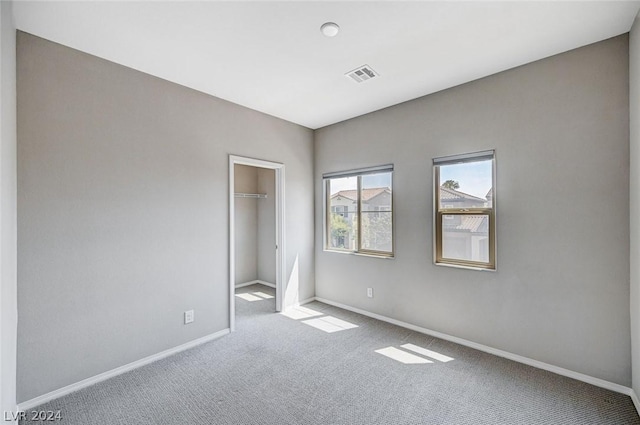 unfurnished bedroom with light colored carpet, a closet, and a walk in closet