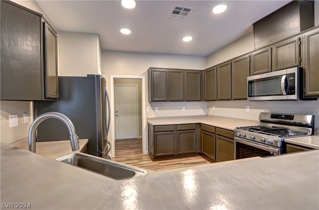 kitchen with light hardwood / wood-style floors, appliances with stainless steel finishes, and sink