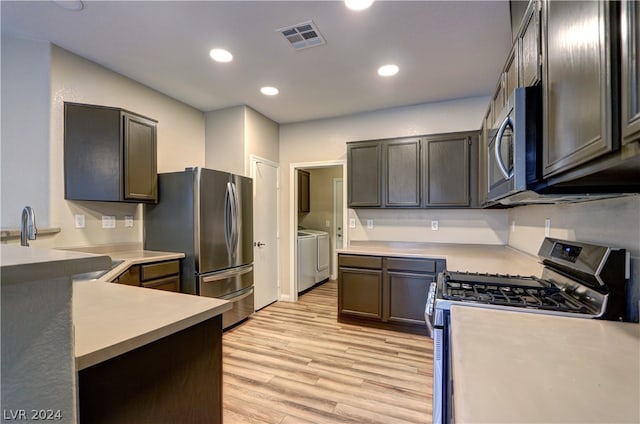 kitchen featuring light hardwood / wood-style floors, appliances with stainless steel finishes, washing machine and dryer, and dark brown cabinetry