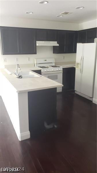 kitchen featuring kitchen peninsula, dark hardwood / wood-style floors, sink, and white appliances