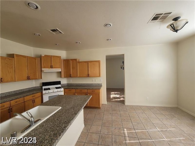 kitchen featuring light tile patterned floors, sink, and white gas stove