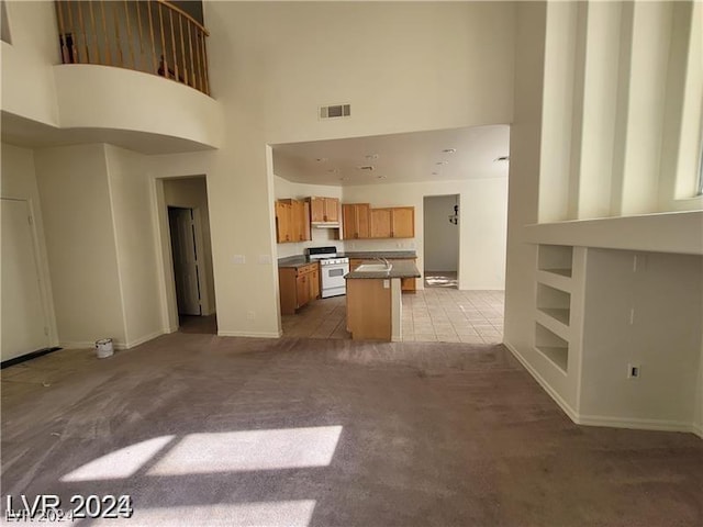 unfurnished living room with carpet flooring, sink, a towering ceiling, and built in shelves