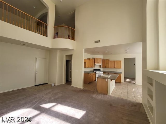 kitchen with light colored carpet, a kitchen island, a kitchen bar, and a towering ceiling