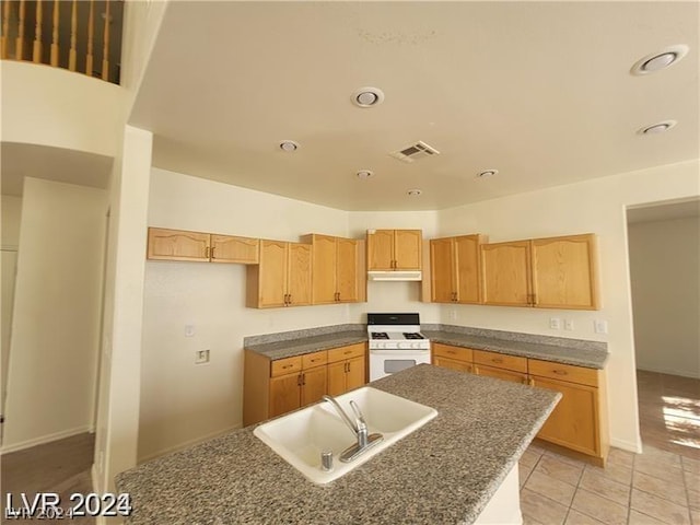 kitchen with a center island, light tile patterned flooring, sink, white range with gas stovetop, and light brown cabinetry