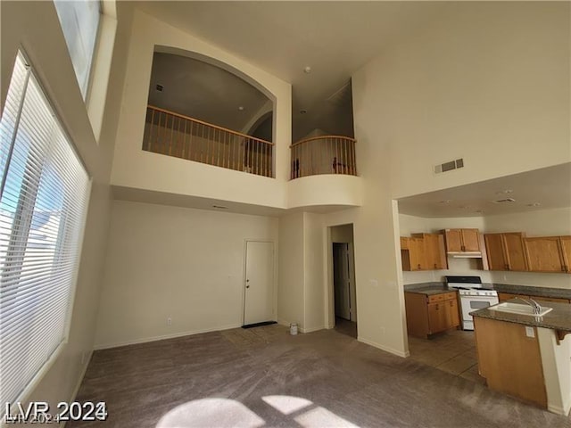 kitchen featuring a towering ceiling, dark carpet, white gas range oven, and a kitchen bar