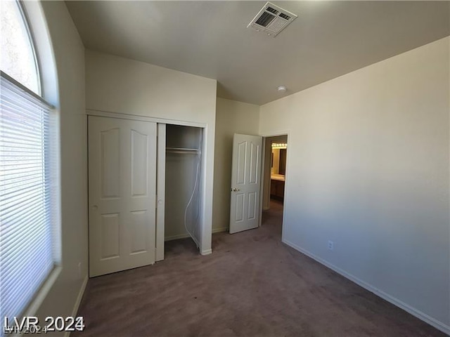 unfurnished bedroom with a closet and dark colored carpet