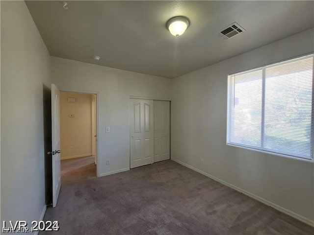 unfurnished bedroom featuring a closet and dark carpet