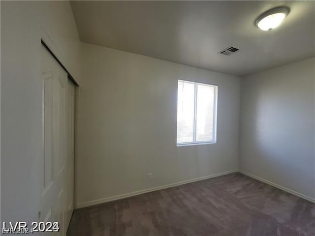 unfurnished room with dark colored carpet