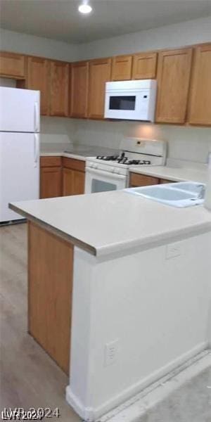 kitchen featuring sink, white appliances, and light hardwood / wood-style flooring