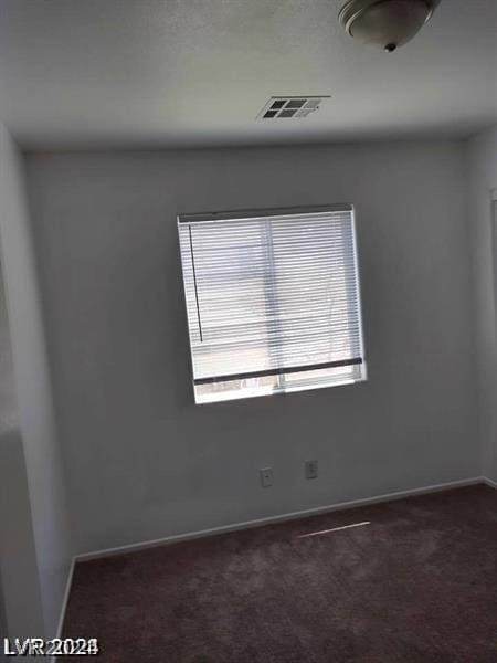 unfurnished room featuring dark carpet