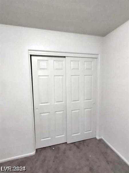 unfurnished bedroom featuring a closet and dark carpet