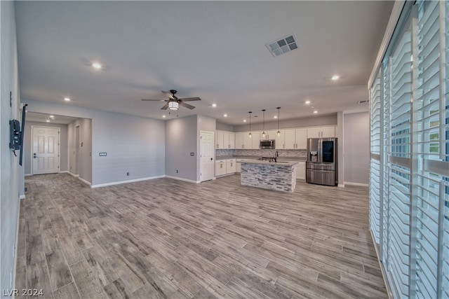 unfurnished living room featuring light hardwood / wood-style floors, sink, and ceiling fan