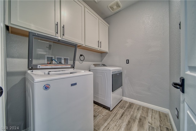 washroom with cabinets, washing machine and dryer, and light wood-type flooring