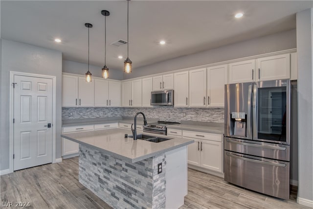 kitchen with hanging light fixtures, decorative backsplash, light wood-type flooring, and stainless steel appliances