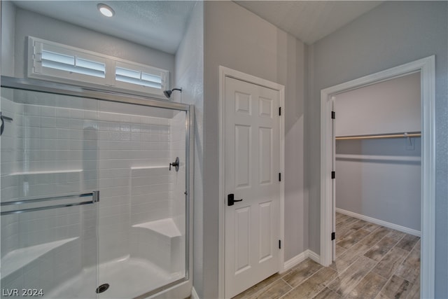 bathroom featuring hardwood / wood-style flooring, a shower with shower door, and a textured ceiling